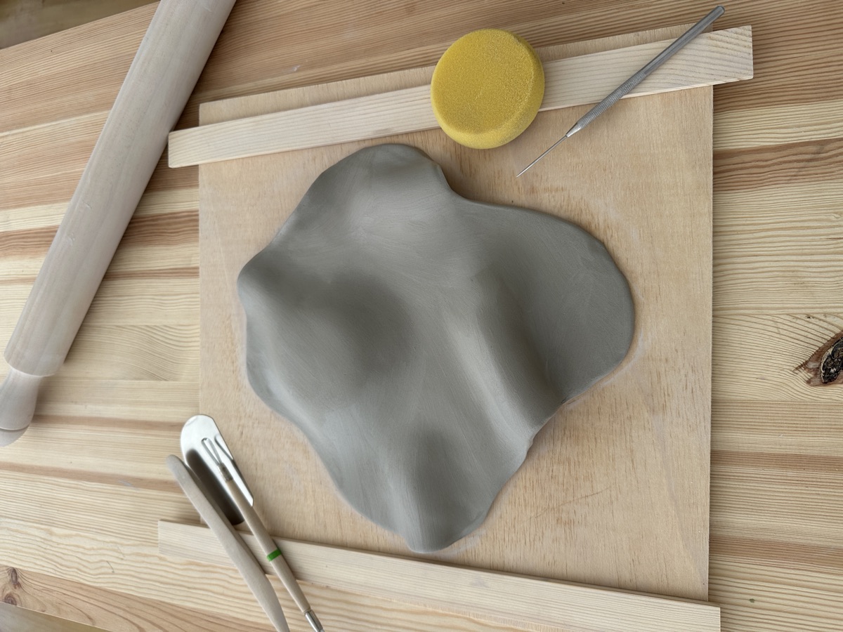 Forma de barro modelada à mão e ferramentas de cerâmica sobre a mesa